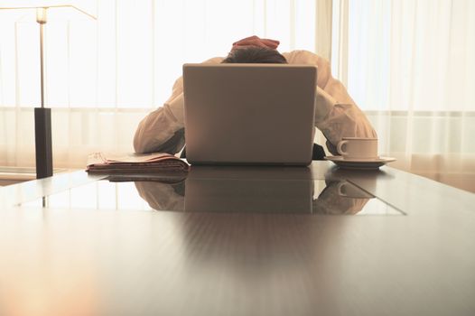 Caucasian businessman hiding behind laptop themes of frustration despair unrecognisable