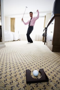 Businessman playing golf in hotel room themes of golf wasting time hobbies