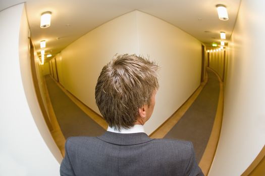 A businessman looking down the corridoor of a hotel themes of travel working late arrival choice