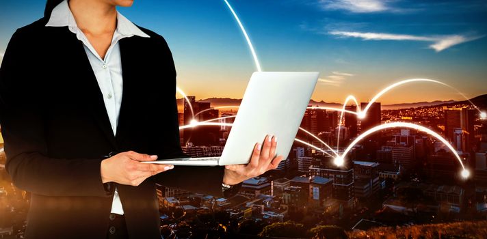 Cropped image of businesswoman holding laptop computer against beautiful view of city skyline