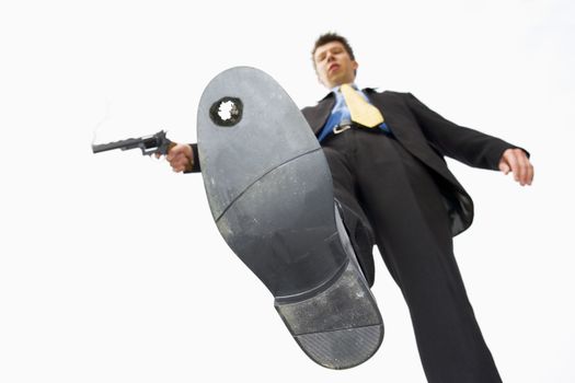 Low angle of a Businessman who has accidently shot himself in the foot themes of accident danger problems