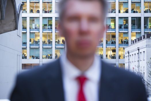 Defocussed businessman looking at the camera at dusk themes of deadlines rush hour departure