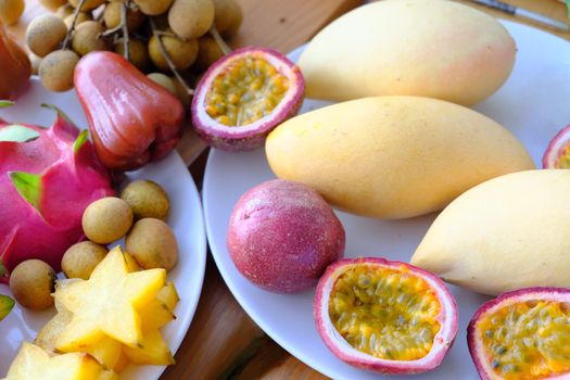 mix tropical fruits longan, mango, Rose apples, dragon fruit, Carambola and whole and cut passion fruits (maracuya) on the plate. 