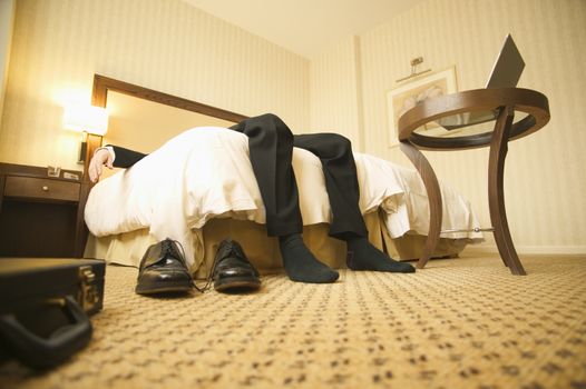 Exhausted businessman laying on hotel bed themes of travel working late exhaustion