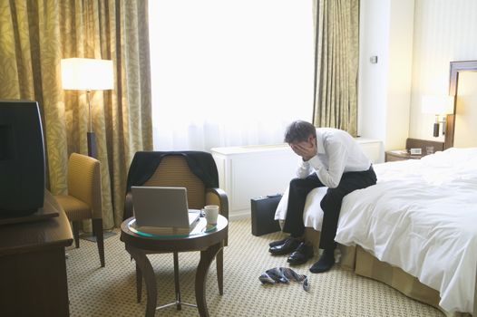 Stressed businessman sitting on hotel bed themes of frustration stress despair