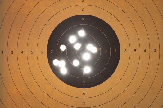 Close up of a shooting target with backlit bullet holes themes of accuracy aim success