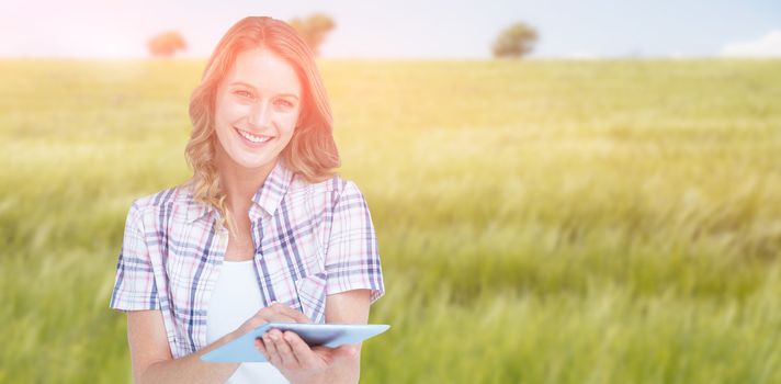 Pretty hipster using tablet  against green meadow