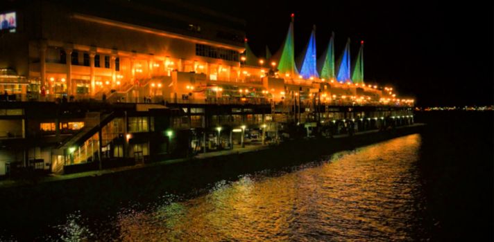 Illuminated buildings by river in city at night