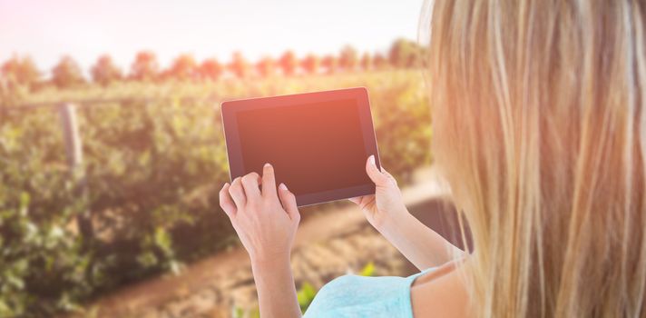 Rear view of woman using tablet pc against plants growing on field
