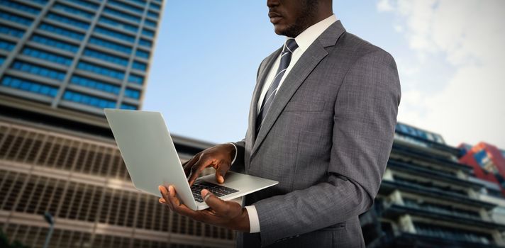 Midsection of businessman using laptop against building against cloudy sky