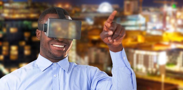 Man pointing while wearing virtual reality headset against illuminated beautiful buildings in city