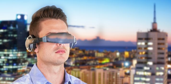 Young man wearing virtual reality simulator against illuminated buildings in city against sky