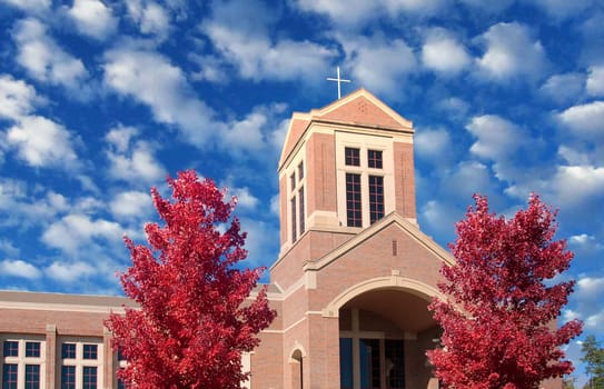 A brick church rising into a blue sky in Autumn