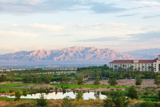 A luxury golf resort in the desert with purple mountains in the distance