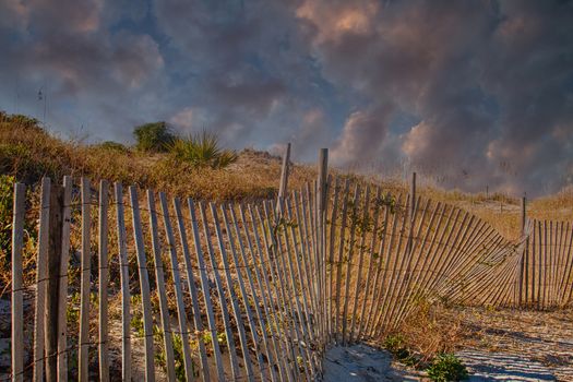 Wood fence by sand dunes on a beach under clear blue skies