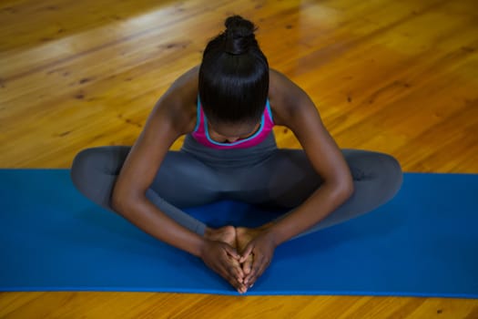 Fit woman doing stretching exercise on mat in fitness studio