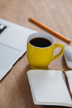 Cup of coffee with laptop, organizer, pencil and mouse arranged on wooden background