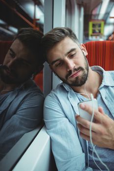 Executive looking at mobile phone while listening music in train