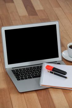 Cup of coffee with laptop, organizer, maker and pen on wooden background