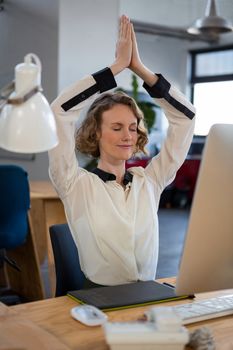 Female graphic designer performing yoga in creative office