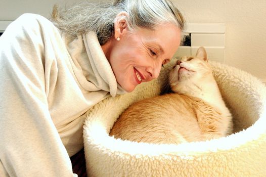 Mature female blond beauty bonding with her cat at home.