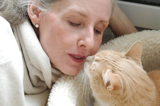 Mature female blond beauty bonding with her cat at home.