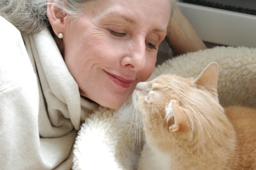 Mature female blond beauty bonding with her cat at home.