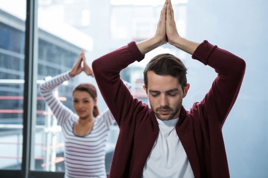 Man and woman doing yoga in office