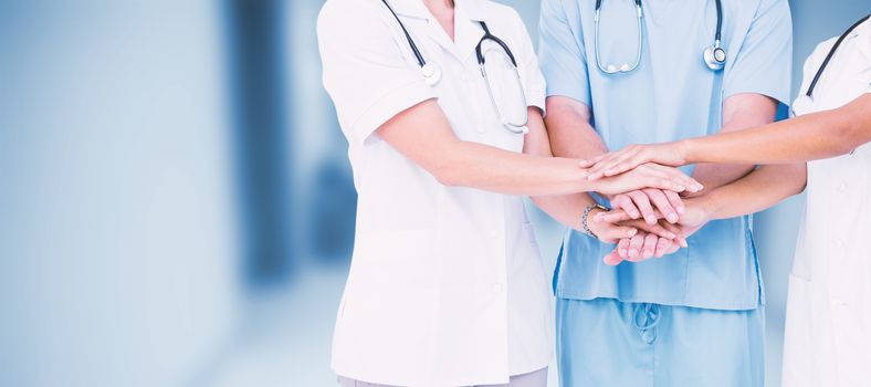 Midsection of doctors putting hands together against dental equipment