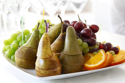 On a plate of pears, grapes, oranges