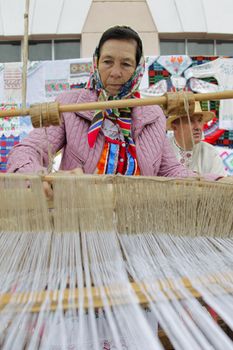 The old woman behind the spinning machine.Work behind a spinning machine.Belarusian woman