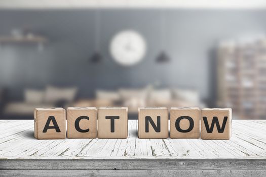 Act now message sign on a wooden desk in a room with ineriors