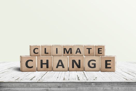 Climate change sign made of wooden cubes on a white desk with a green background
