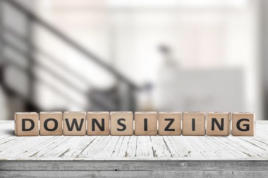 Downsizing message sign made of wood on a white desk in an office environment