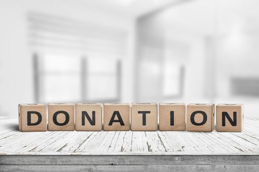 Wooden donation sign on a worn desk in a bright room with lights