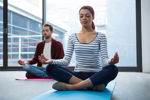 Man and woman doing yoga in office