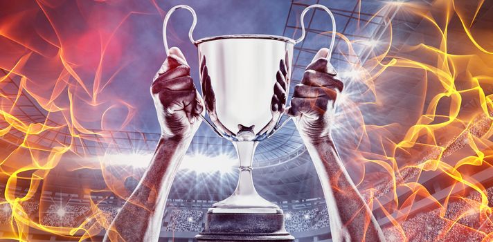 Abstract orange glowing black background against composite image of cropped hand of athlete holding trophy