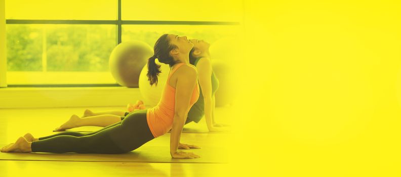Fit women doing the cobra pose in fitness studio against glowing background