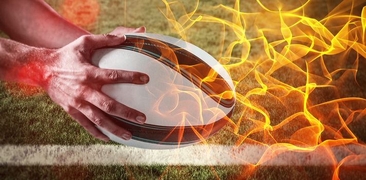 Abstract orange glowing black background against cropped image of hand rugby ball