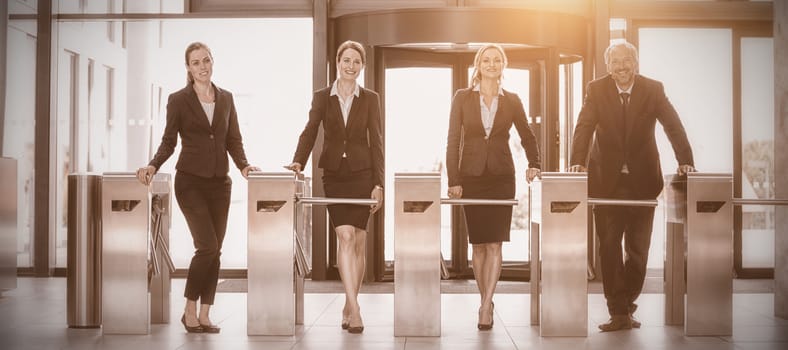 Businesspeople standing at turnstile gate in office