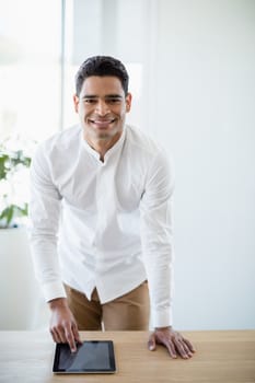 Portrait of smiling business executive using digital tablet at desk in office