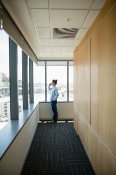 Business executive talking on mobile phone in corridor at office