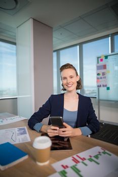 Portrait of business executive using her mobile phone at office