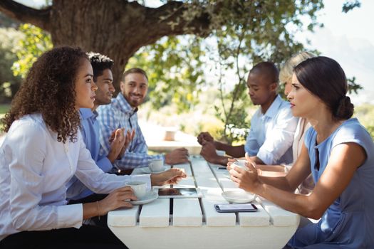Group of friends interacting with each other in outdoors restaurant