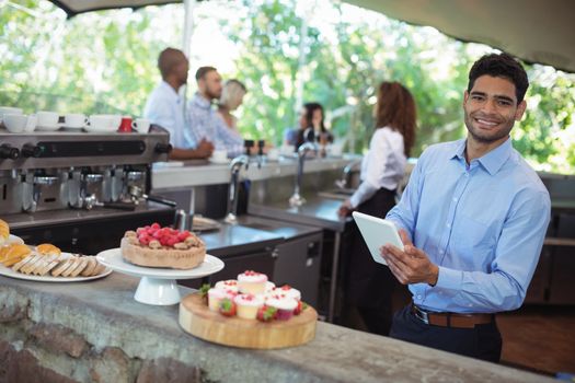 Young waiter using digital tablet at outdoors cafe