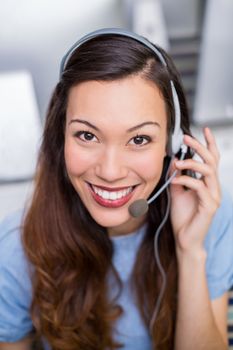 Portrait of female customer service executive talking on headset at desk in office