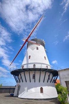 Old windmill rising up to a blue sky in the summer in white colors