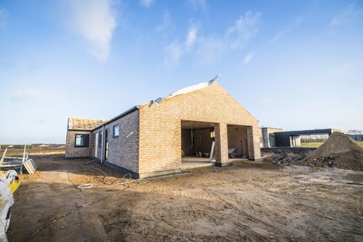 Brick house construction site in a new neighborhood under a blue sky
