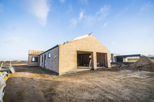 Brick house construction site in a new neighborhood under a blue sky