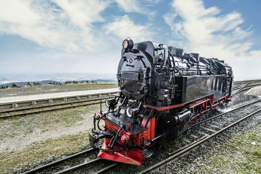 Locomotive on railroad tracks at a station under a blue sky